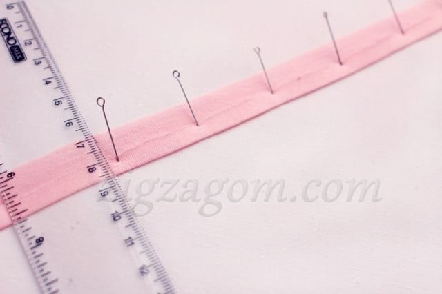 Выкроить поперечную бейку из розового трикотажа шириной 2,5 см. и длиной 32 см.